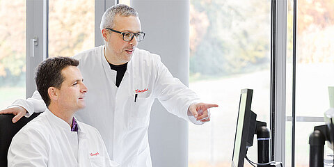 Employees in white coats at the computer